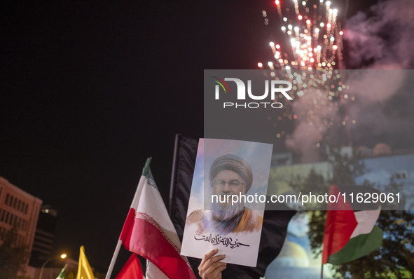 An Iranian man holds a portrait of Lebanon's Hezbollah Secretary General, Hassan Nasrallah, who was killed in an Israeli air strike in the s...