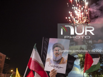 An Iranian man holds a portrait of Lebanon's Hezbollah Secretary General, Hassan Nasrallah, who was killed in an Israeli air strike in the s...