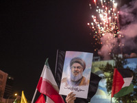 An Iranian man holds a portrait of Lebanon's Hezbollah Secretary General, Hassan Nasrallah, who was killed in an Israeli air strike in the s...