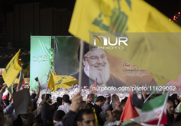 An Iranian man waves a flag of Lebanon's Hezbollah in front of a portrait of Lebanon's Hezbollah Secretary General, Hassan Nasrallah, who wa...