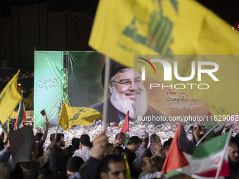 An Iranian man waves a flag of Lebanon's Hezbollah in front of a portrait of Lebanon's Hezbollah Secretary General, Hassan Nasrallah, who wa...