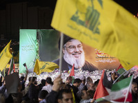 An Iranian man waves a flag of Lebanon's Hezbollah in front of a portrait of Lebanon's Hezbollah Secretary General, Hassan Nasrallah, who wa...