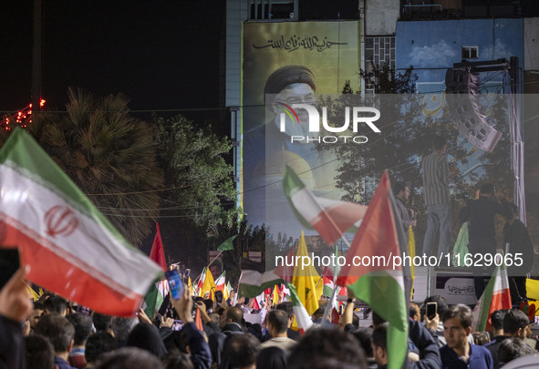 Iranians wave Iranian and Palestinian flags under a giant portrait of Lebanon's Hezbollah Secretary General, Hassan Nasrallah, in Tehran, Ir...