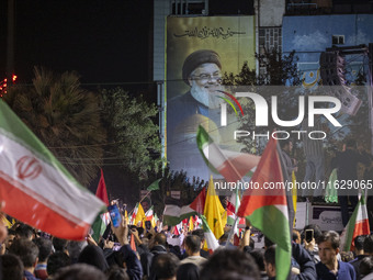 Iranians wave Iranian and Palestinian flags under a giant portrait of Lebanon's Hezbollah Secretary General, Hassan Nasrallah, in Tehran, Ir...