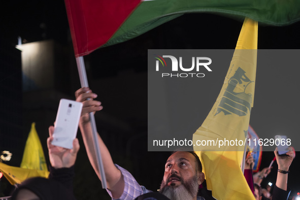 An Iranian man waves a Palestinian flag while celebrating Iran's missile attack against Israel in Tehran, Iran, on October 1, 2024. Iran lau...