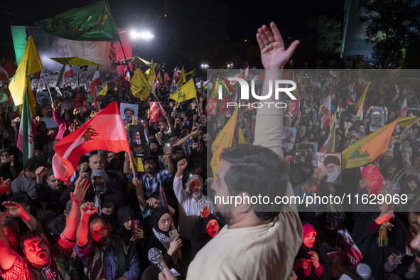 Iranians wave flags and shout anti-Israeli and anti-U.S. slogans while celebrating Iran's missile attack against Israel in Tehran, Iran, on...