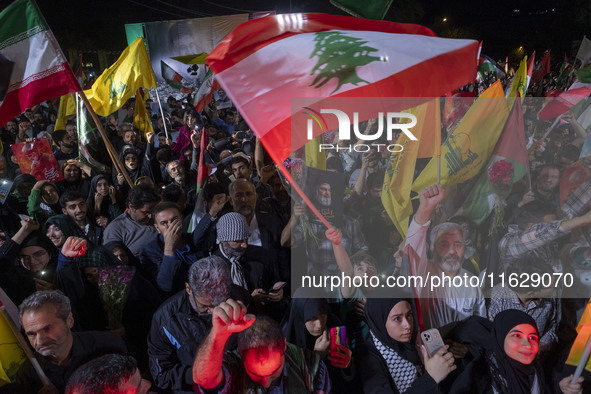 Iranians wave flags and shout anti-Israeli and anti-U.S. slogans while celebrating Iran's missile attack against Israel in Tehran, Iran, on...