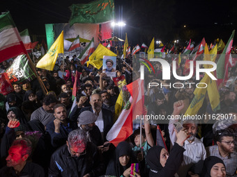 Iranians wave flags and shout anti-Israeli and anti-U.S. slogans while celebrating Iran's missile attack against Israel in Tehran, Iran, on...