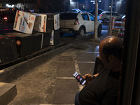 An Iranian man sits on a sidewalk while checking the latest news about Iran's missile attack against Israel in Tehran, Iran, on October 1, 2...