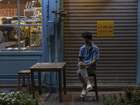 A young Iranian worker sits outside a cafe in downtown Tehran, Iran, on October 1, 2024, while checking the latest news about Iran's missile...