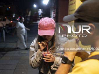 Iranian youths drink fruit juice while standing on a sidewalk in downtown Tehran, Iran, on October 1, 2024, after Iran's missile attack agai...