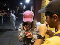 Iranian youths drink fruit juice while standing on a sidewalk in downtown Tehran, Iran, on October 1, 2024, after Iran's missile attack agai...