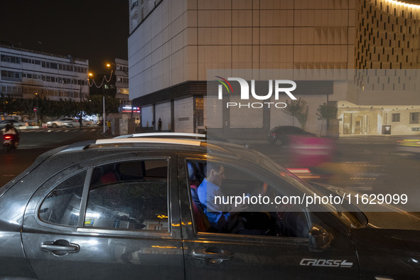 An Iranian man sits in his vehicle in downtown Tehran, Iran, on October 1, 2024, while checking the latest news about Iran's missile attack...