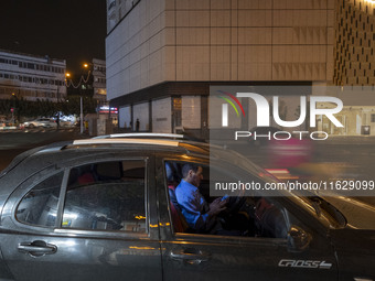 An Iranian man sits in his vehicle in downtown Tehran, Iran, on October 1, 2024, while checking the latest news about Iran's missile attack...