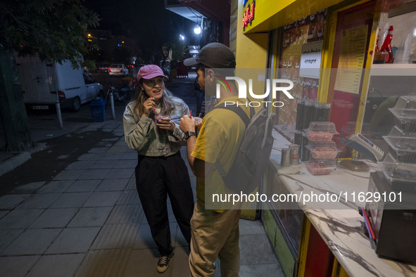 Iranian youths drink fruit juice while standing on a sidewalk in downtown Tehran, Iran, on October 1, 2024, after Iran's missile attack agai...