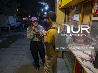 Iranian youths drink fruit juice while standing on a sidewalk in downtown Tehran, Iran, on October 1, 2024, after Iran's missile attack agai...