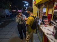 Iranian youths drink fruit juice while standing on a sidewalk in downtown Tehran, Iran, on October 1, 2024, after Iran's missile attack agai...