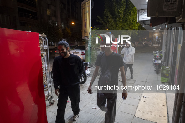 Iranian youths walk along a sidewalk in downtown Tehran, Iran, on October 1, 2024, after Iran's missile attack against Israel. Iran launches...