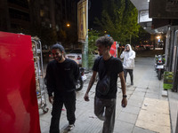 Iranian youths walk along a sidewalk in downtown Tehran, Iran, on October 1, 2024, after Iran's missile attack against Israel. Iran launches...