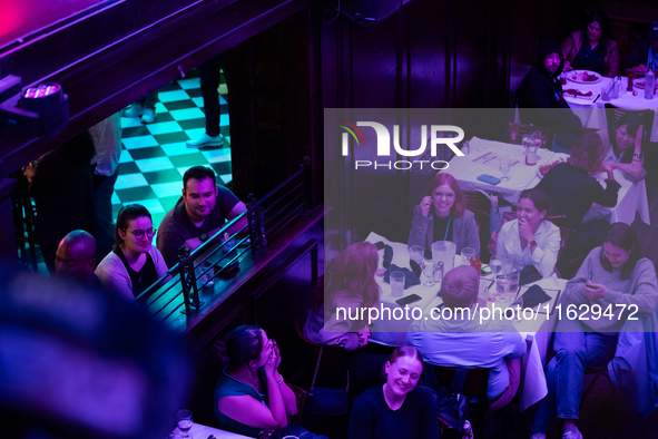 People watch the vice presidential debate under the pink and purple lights at Madhatter in Washington, DC, on October 1, 2024.  It was the o...