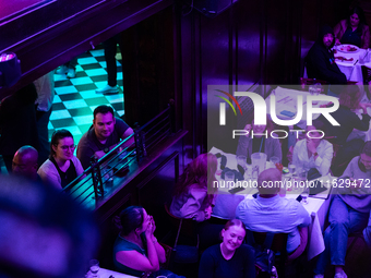 People watch the vice presidential debate under the pink and purple lights at Madhatter in Washington, DC, on October 1, 2024.  It was the o...