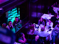 People watch the vice presidential debate under the pink and purple lights at Madhatter in Washington, DC, on October 1, 2024.  It was the o...