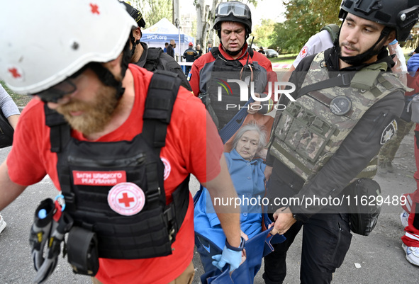 Medical workers and a policeman carry a 90-year-old local resident, Valentyna, on a stretcher after she sustains injuries as a result of Rus...