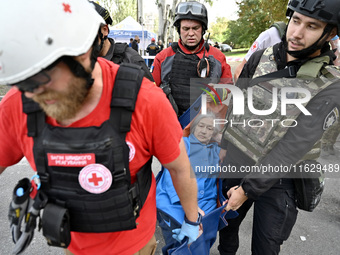 Medical workers and a policeman carry a 90-year-old local resident, Valentyna, on a stretcher after she sustains injuries as a result of Rus...