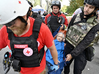 Medical workers and a policeman carry a 90-year-old local resident, Valentyna, on a stretcher after she sustains injuries as a result of Rus...