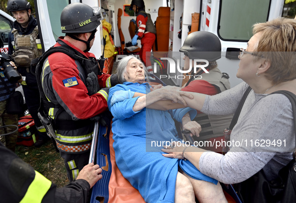 Medical workers and a policeman carry a 90-year-old local resident, Valentyna, on a stretcher after she sustains injuries as a result of Rus...