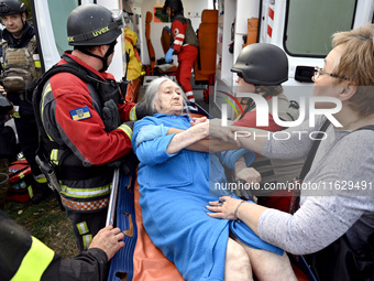 Medical workers and a policeman carry a 90-year-old local resident, Valentyna, on a stretcher after she sustains injuries as a result of Rus...