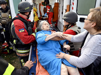 Medical workers and a policeman carry a 90-year-old local resident, Valentyna, on a stretcher after she sustains injuries as a result of Rus...