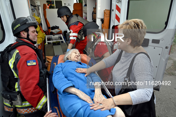 Medical workers and a policeman carry a 90-year-old local resident, Valentyna, on a stretcher after she sustains injuries as a result of Rus...