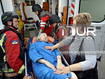 Medical workers and a policeman carry a 90-year-old local resident, Valentyna, on a stretcher after she sustains injuries as a result of Rus...