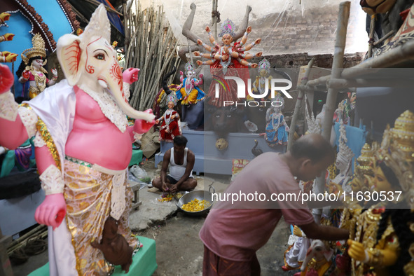 An artisan prepares food in front of idols of the Hindu goddess Durga at a workshop ahead of the Durga Puja festival in Kolkata, India, on O...