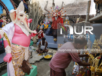 An artisan prepares food in front of idols of the Hindu goddess Durga at a workshop ahead of the Durga Puja festival in Kolkata, India, on O...