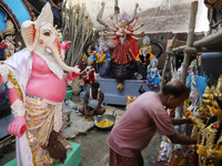 An artisan prepares food in front of idols of the Hindu goddess Durga at a workshop ahead of the Durga Puja festival in Kolkata, India, on O...