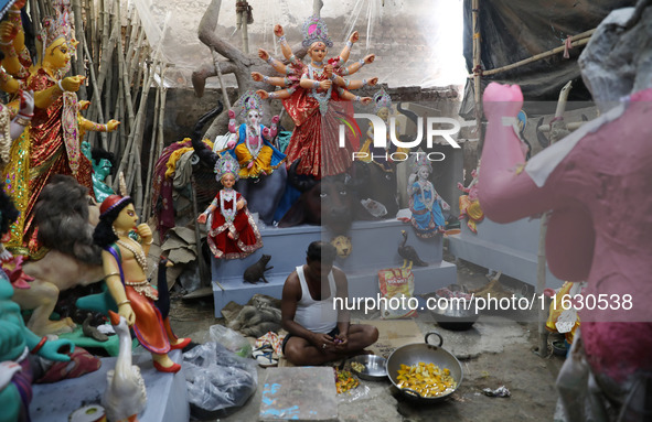 An artisan prepares food in front of idols of the Hindu goddess Durga at a workshop ahead of the Durga Puja festival in Kolkata, India, on O...