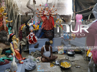 An artisan prepares food in front of idols of the Hindu goddess Durga at a workshop ahead of the Durga Puja festival in Kolkata, India, on O...