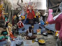 An artisan prepares food in front of idols of the Hindu goddess Durga at a workshop ahead of the Durga Puja festival in Kolkata, India, on O...