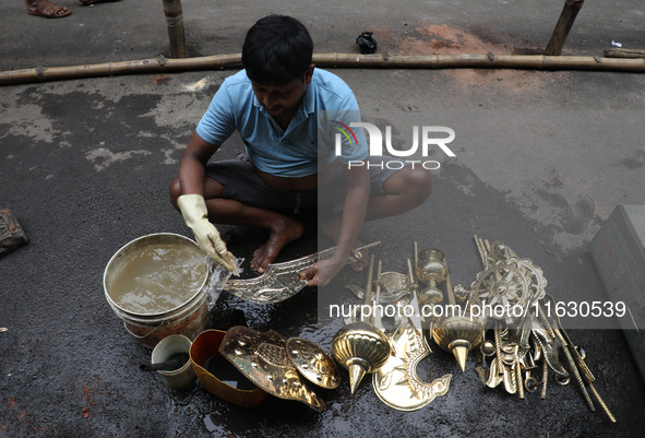 A worker cleans artificial weapons which will be used to decorate idols of the Hindu goddess Durga at a workshop ahead of the Durga Puja fes...