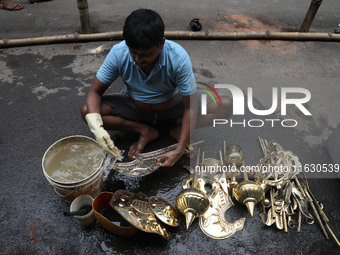 A worker cleans artificial weapons which will be used to decorate idols of the Hindu goddess Durga at a workshop ahead of the Durga Puja fes...