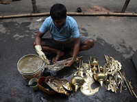 A worker cleans artificial weapons which will be used to decorate idols of the Hindu goddess Durga at a workshop ahead of the Durga Puja fes...