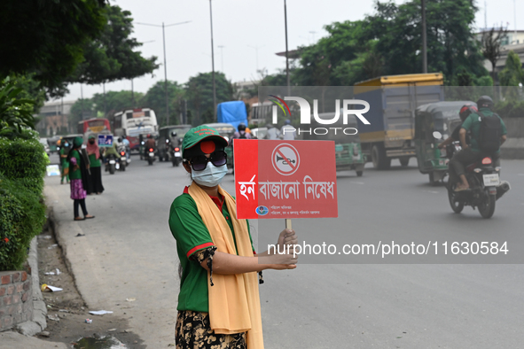 A group of volunteers holds a placard and a banner amid traffic during the No Horn campaign at Airport Road in Dhaka, Bangladesh, on October...