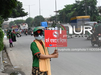 A group of volunteers holds a placard and a banner amid traffic during the No Horn campaign at Airport Road in Dhaka, Bangladesh, on October...