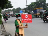 A group of volunteers holds a placard and a banner amid traffic during the No Horn campaign at Airport Road in Dhaka, Bangladesh, on October...