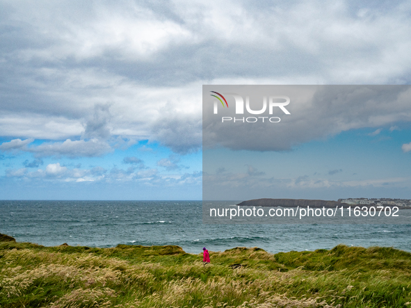 A person walks along the cliffs of the Causeway Coast Area in County Antrim, Northern Ireland, on July 2024. 