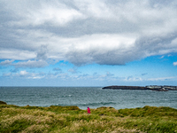 A person walks along the cliffs of the Causeway Coast Area in County Antrim, Northern Ireland, on July 2024. (