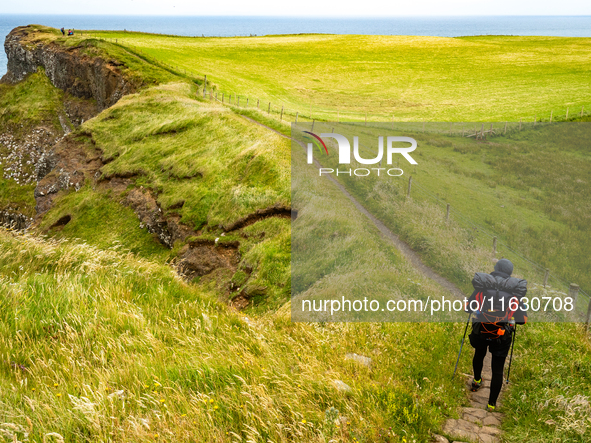 A person walks along the cliffs of the Causeway Coast Area in County Antrim, Northern Ireland, on July 2024. 