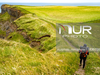 A person walks along the cliffs of the Causeway Coast Area in County Antrim, Northern Ireland, on July 2024. (